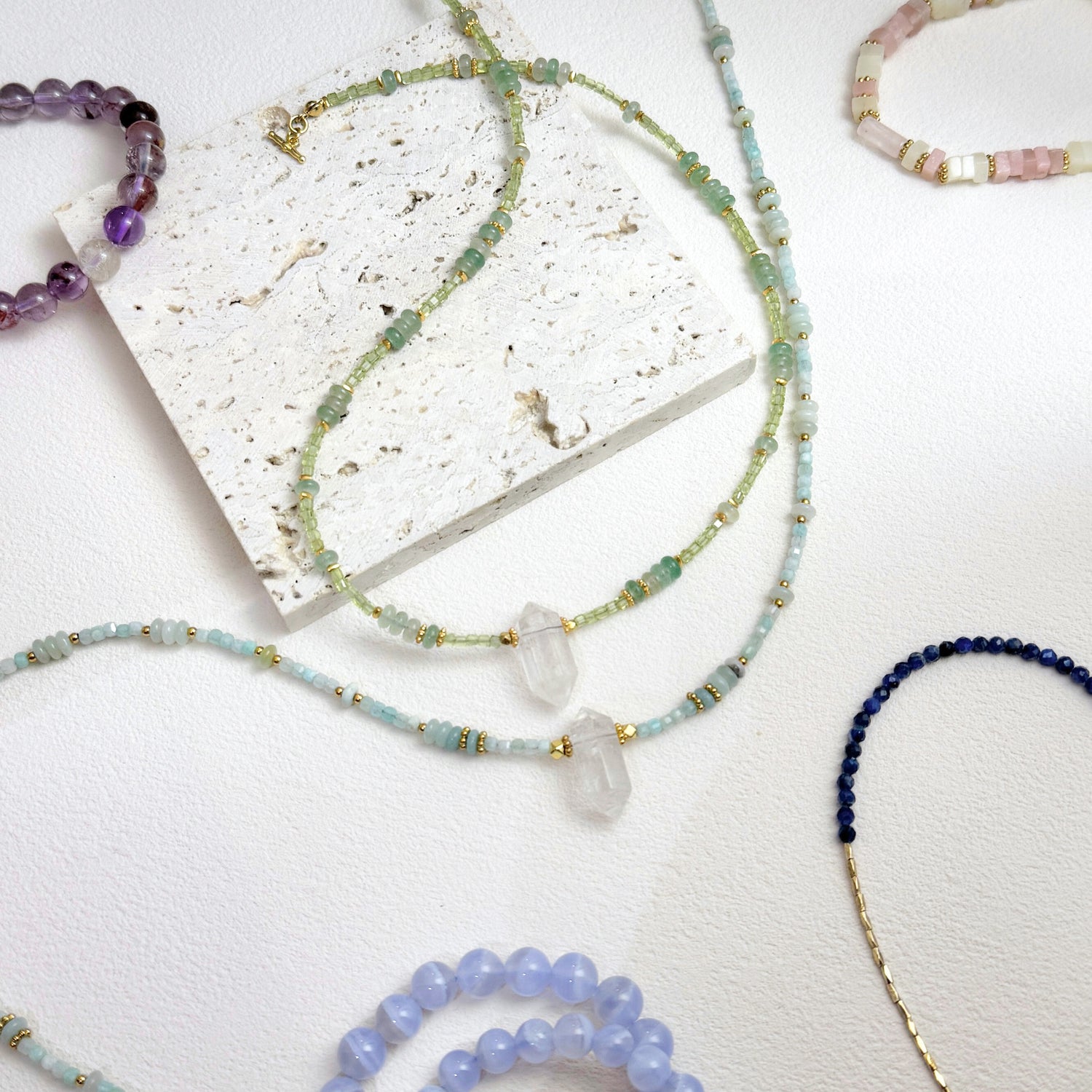 Collection of beaded necklaces on a textured white surface
